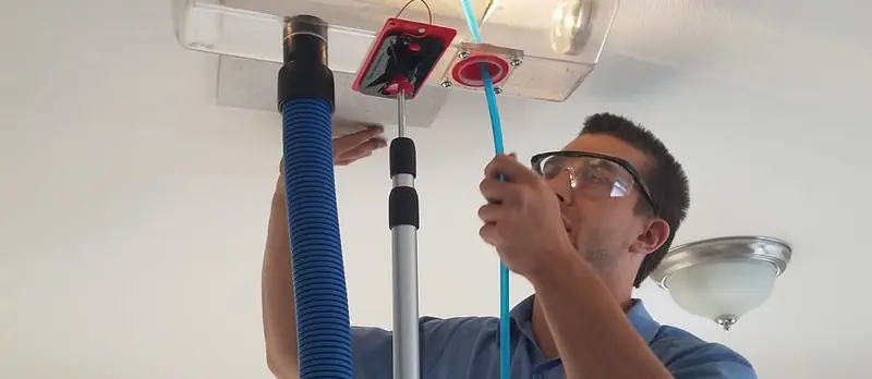 Miracle Men technician cleaning a ceiling air vent with a vacuum hose