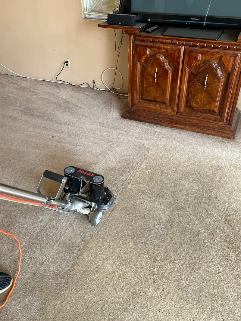 Rotovac working on carpet by a wooden entertainment cabinet