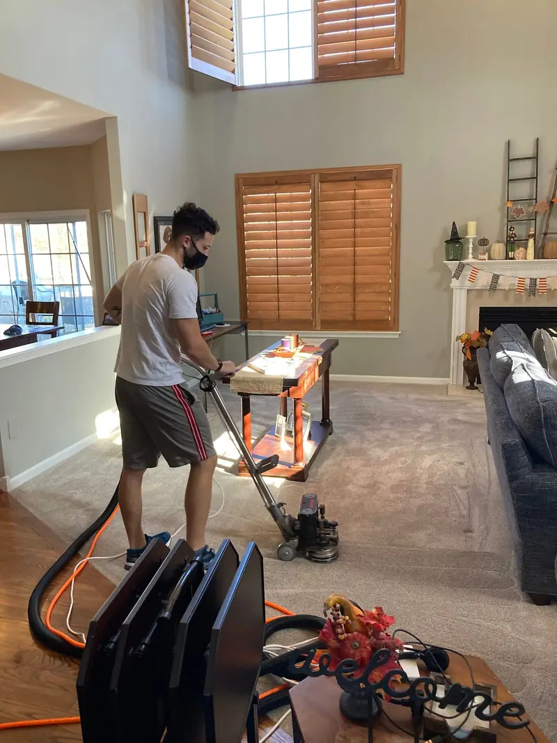 Technician cleaning a great room carpet with equipment set up nearby